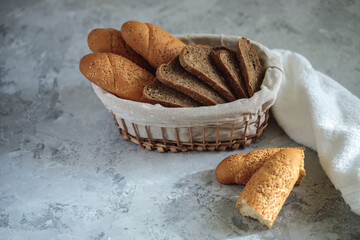 Fresh bread baguette with sesame seeds and slices of rye bread are in the breadbox on the table. Bakery. Flat lay. Close-up, minimalism. - obrazy, fototapety, plakaty