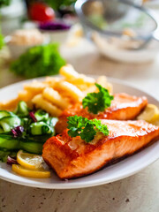Fototapeta na wymiar Fried salmon, French fries and vegetables