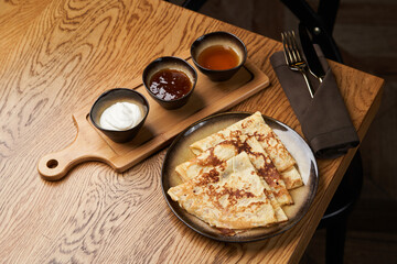 Homemade pancakes with jam, honey and sour cream bowls, close-up