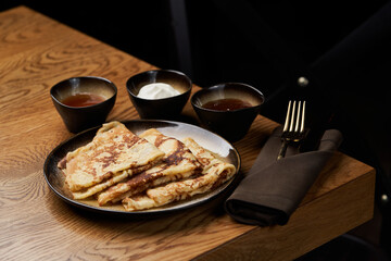 Homemade pancakes with jam, honey and sour cream bowls, close-up