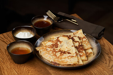 Homemade pancakes with jam, honey and sour cream bowls, close-up