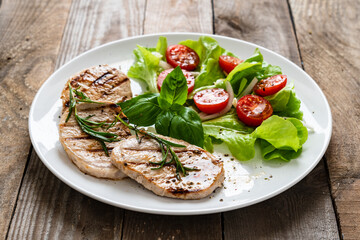 Grilled steaks with vegetable salad on white plate