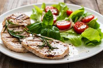Grilled steaks with vegetable salad on white plate