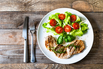 Grilled steaks with vegetable salad on white plate