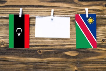 Hanging flags of Libya and Namibia attached to rope with clothes pins with copy space on white note...