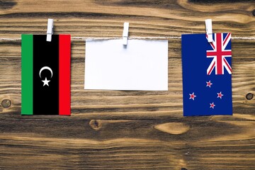 Hanging flags of Libya and New Zealand attached to rope with clothes pins with copy space on white...