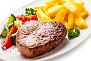 Grilled steaks, French fries and vegetables