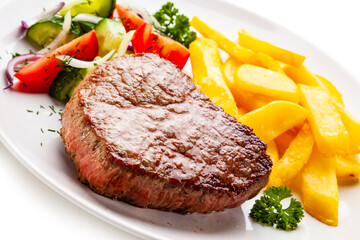 Grilled steaks, French fries and vegetables