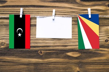 Hanging flags of Libya and Seychelles attached to rope with clothes pins with copy space on white...