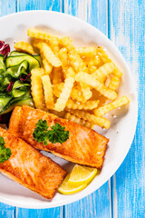 Fried salmon, French fries and vegetables