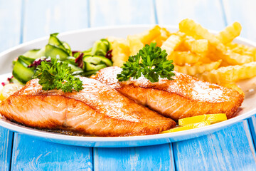 Fried salmon, French fries and vegetables