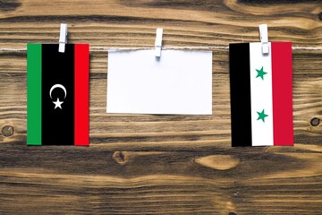 Hanging flags of Libya and Syria attached to rope with clothes pins with copy space on white note...