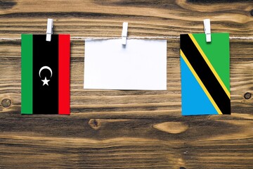 Hanging flags of Libya and Tanzania attached to rope with clothes pins with copy space on white...