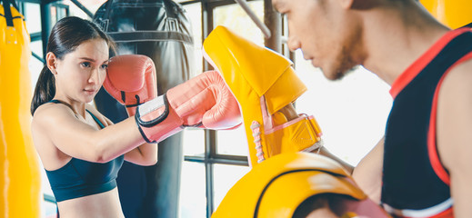 Female boxer hitting a huge punching bag at a boxing studio. Woman boxer training hard. Thai boxer...