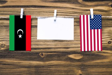 Hanging flags of Libya and United States attached to rope with clothes pins with copy space on...