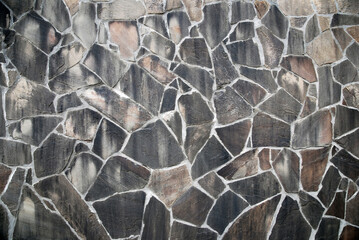 Slate stone texture, natural mudstone wall of irregular polygons in gray brown color