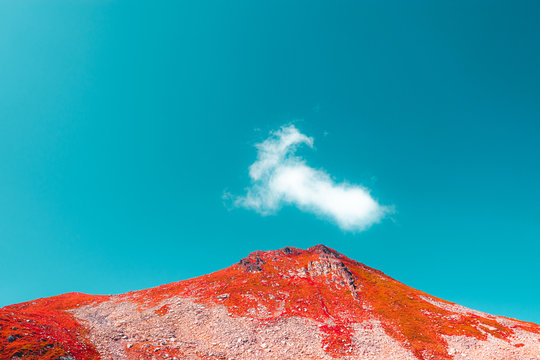 red mountain and cyan blue sky with one cloud