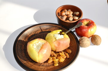 Vegetarian, diet food. On the table is a plate with apples baked with cottage cheese and honey, nuts and raisins.