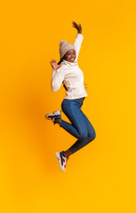 Fototapeta na wymiar Carefree black girl jumping in the air over yellow background