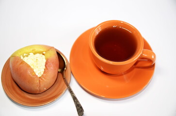 Vegetarian, diet food. On the table is a plate with an apple baked with cottage cheese, honey and a cup of black tea.