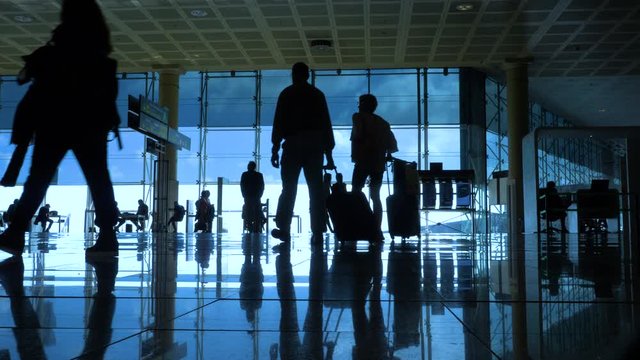 International airport with business people pulling trolley bags arriving and departing terminal tourists travelling and walking in lobby with big windows and blue sky 4k footage
