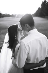 Black and white photo of cheerful emotional newlyweds who enjoy each other. Gorgeous bride and handsome groom. Luxury elegant wedding couple kissing and embracing. Romantic moment.Together. Wedding. 