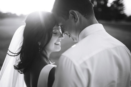 Black and white photo of cheerful emotional newlyweds who enjoy each other. Gorgeous bride and handsome groom. Luxury elegant wedding couple kissing and embracing. Romantic moment.Together. Wedding. 