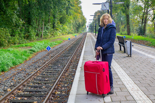 Dutch woman with suitcase stands on train station