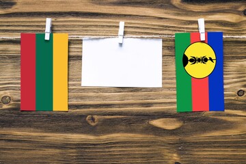 Hanging flags of Lithuania and New Caledonia attached to rope with clothes pins with copy space on...