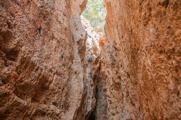 Male rock climber on challenging route in cave. Young man lead climbing in a beautiful grotto. The climber overcomes a difficult route. The athlete trains on a natural relief. Climbing in Spain.