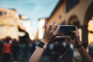 Nahaufnahme einer Frau die ein Smartphone hält und ein Foto von der hektischen Stadt macht. Touristin in Florenz mit schönem Bokeh.