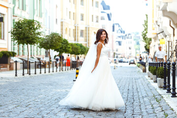Young  elegant  bride in a white dress in the city. Beautyful  bride with luxury make-up and hairstyle. Happy newlywed woman. Smiling bride. Wedding day. Fashion bride.