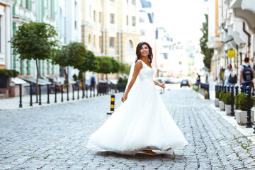 Young  elegant  bride in a white dress in the city. Beautyful  bride with luxury make-up and hairstyle. Happy newlywed woman. Smiling bride. Wedding day. Fashion bride.
