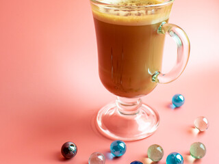 Wonderful hot drink in an amazing glass on a pink background with pebbles.