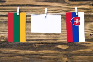 Hanging flags of Lithuania and Slovakia attached to rope with clothes pins with copy space on white...