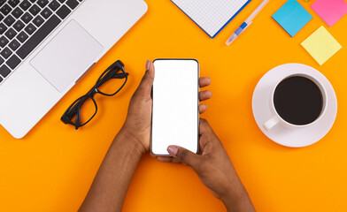 Black woman using smartphone with blank screen at workplace