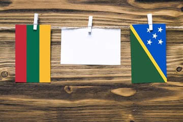 Hanging flags of Lithuania and Solomon Islands attached to rope with clothes pins with copy space...