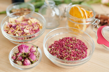 Three bowls with dry rose petals and rosebuds and small jar with orange slices