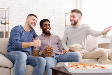 Three football fans watching game on TV at home