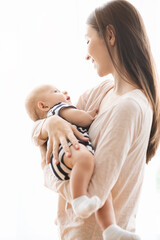 Portrait of beautiful mother lulling her baby in arms