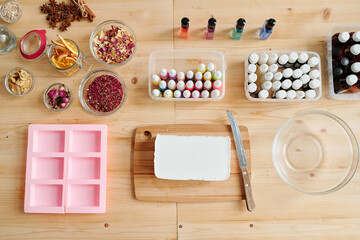 Bar of white hard soap mass on board, bottles with scents and silicone molds