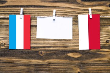 Hanging flags of Luxembourg and Monaco attached to rope with clothes pins with copy space on white...
