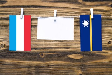 Hanging flags of Luxembourg and Nauru attached to rope with clothes pins with copy space on white...