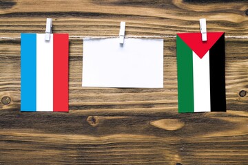 Hanging flags of Luxembourg and Palestine attached to rope with clothes pins with copy space on...
