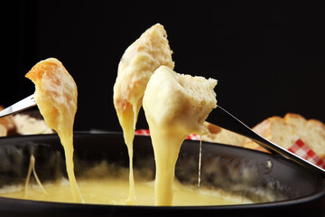 Gourmet Swiss fondue dinner on a winter evening with assorted cheeses on a board alongside a heated...