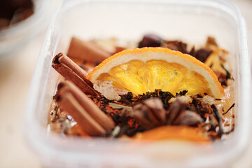 Fresh orange slice, cinnamon sticks and grated dry spices in liquid soap mass