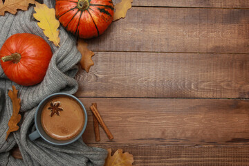 Grey cup of coffee with milk and spices, plaid, yellow oak leaves, orange pumpkins on dark brown...