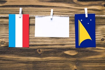 Hanging flags of Luxembourg and Tokelau attached to rope with clothes pins with copy space on white...