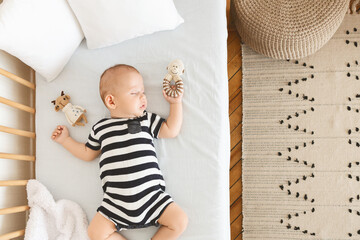 Portrait of sleeping newborn baby holding his toy in hand