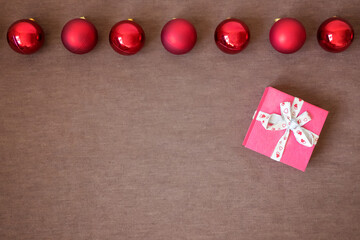 Christmas time banner template on brown background. New Year decoration. Xmas red balls. Flat-lay. New Year concept with gift box.